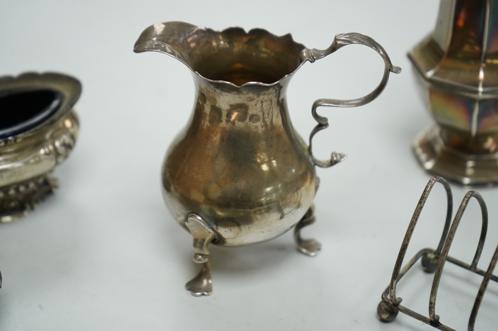 A collection of small silver, including a George III cream jug, London, 1762, 88mm, a George V sugar caster, small five bar toastrack, pair of bonbon dishes, pepperette, dish, two condiment spoons and mustard pot, togeth